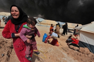 A woman carries her child to escape from the burnt tents at Zattari Syrian refugee camp near Mafraq, Syria, on March 8. A heavy fire broke out and consumed a large number of tents. UNICEF reports that more than two million Syrian children are internally displaced refugees within Syria.
